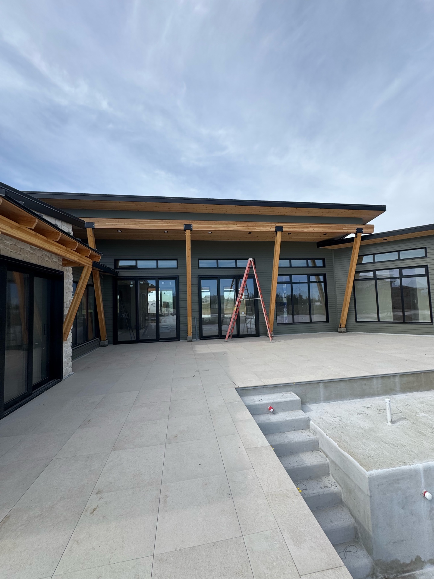 Custom home exterior with pool deck, timber beams, and stone accents