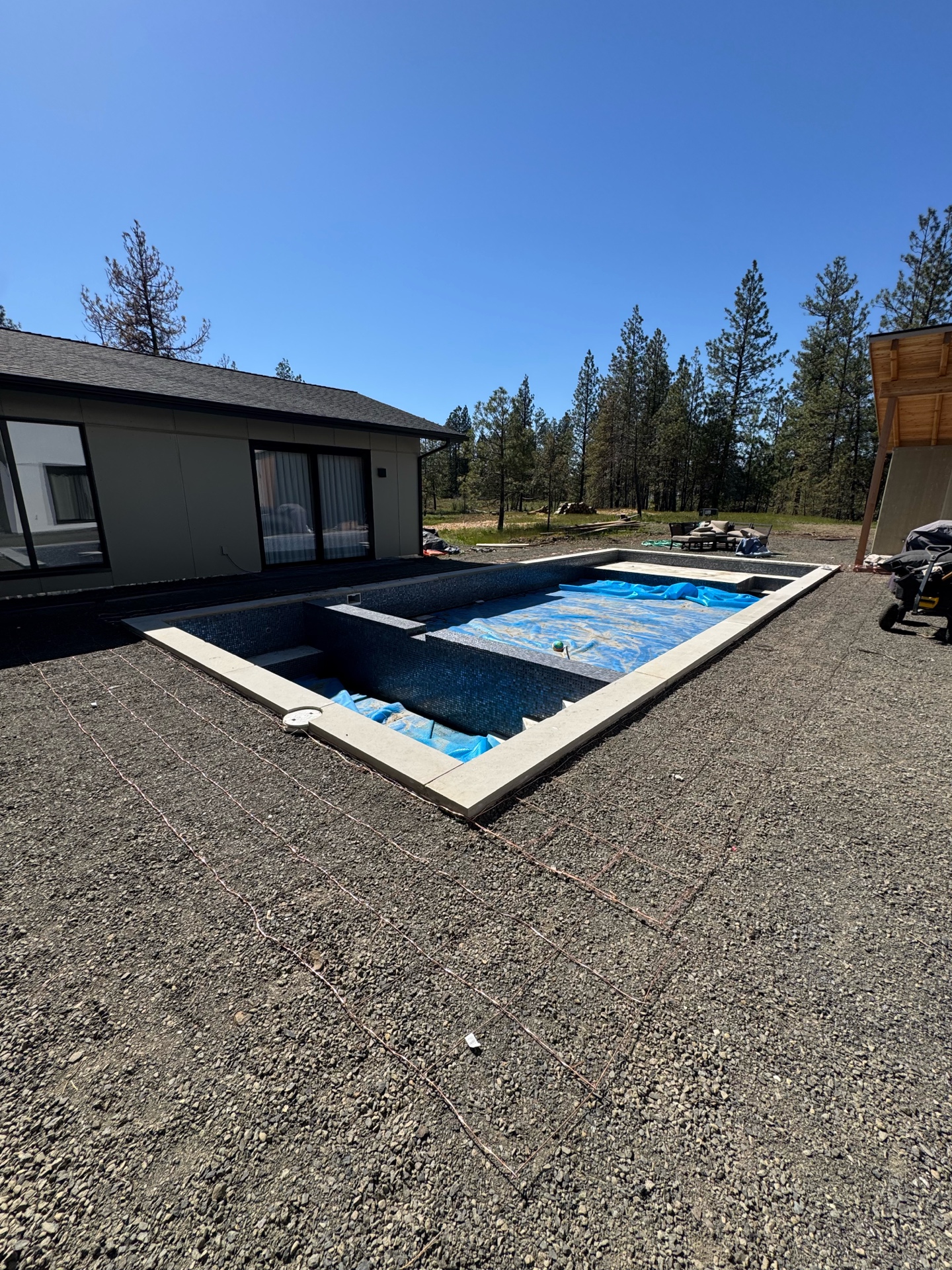 Full view of custom pool with modern home and bonding grid in gravel