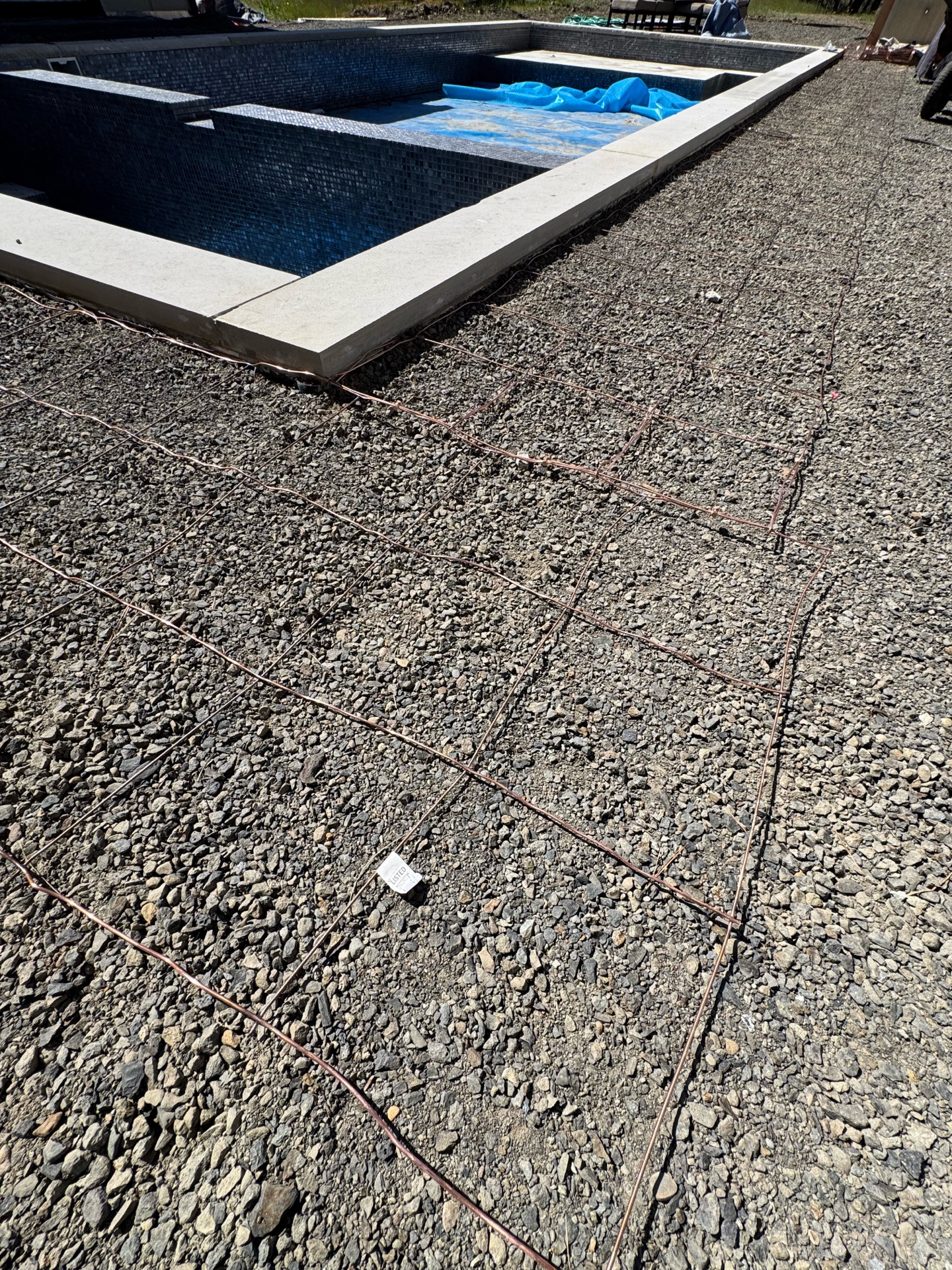 Detailed view of copper bonding grid connections around pool coping