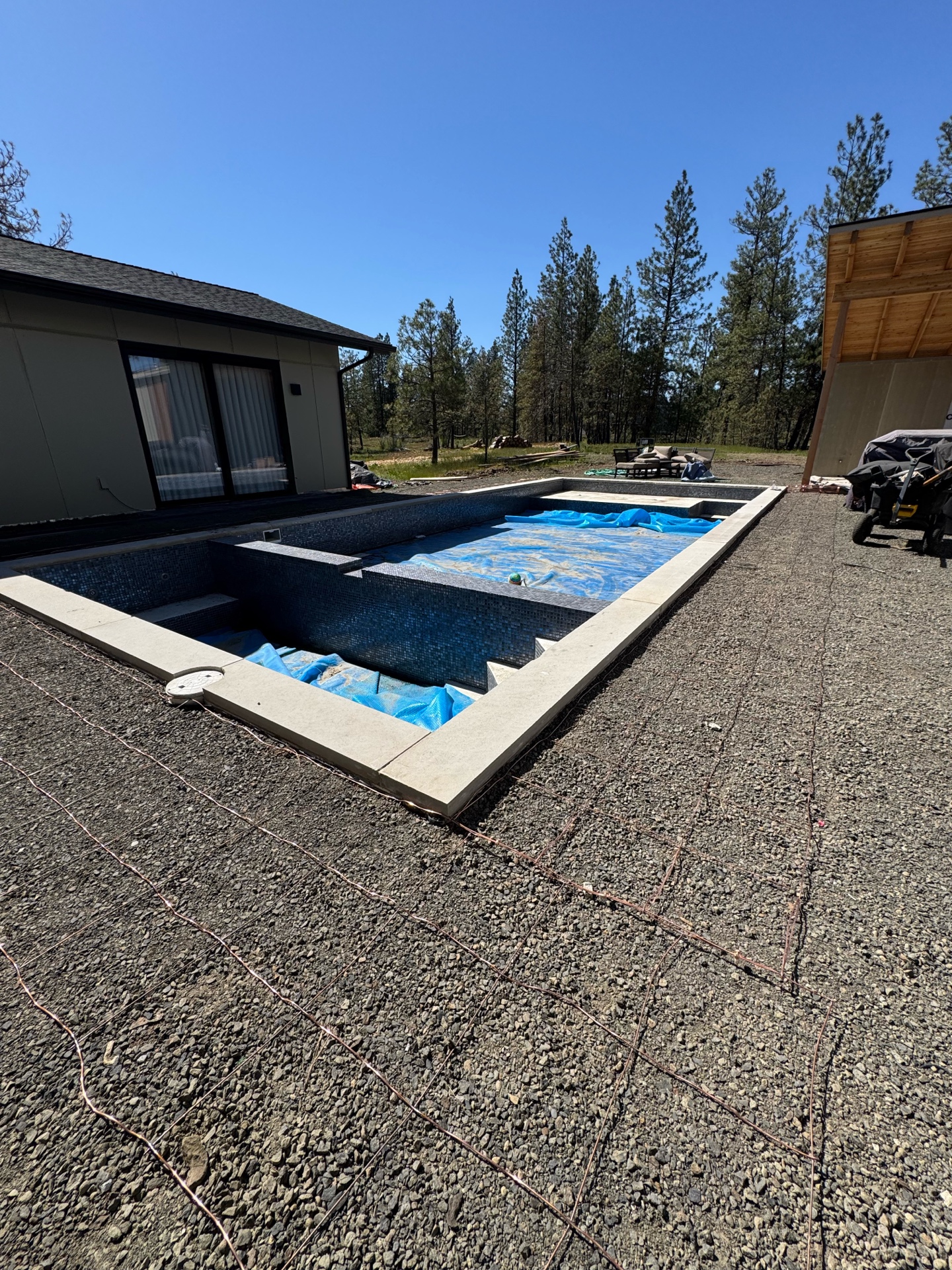 Custom pool and spa with dark tile and bonding grid visible in gravel